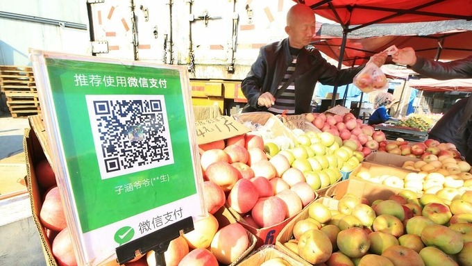 Một người bán quả tại Đại Liên nhận thanh toán bằng mã QR. Ảnh: Nikkei